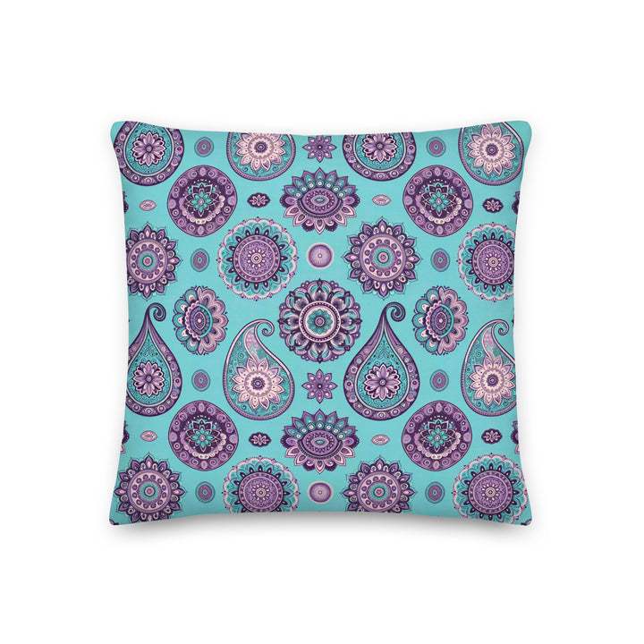 A decorative pillow with an intricate paisley and mandala pattern in shades of lavender, purple, and turquoise on a light turquoise background.