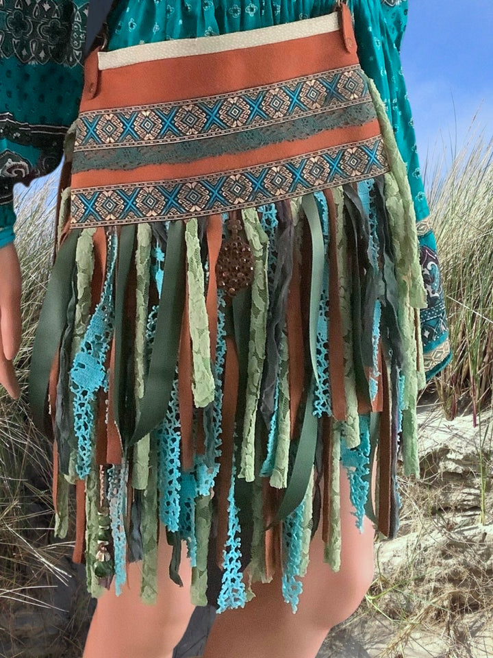 picture of a model in the dunes with a leather boho bag in blue and green