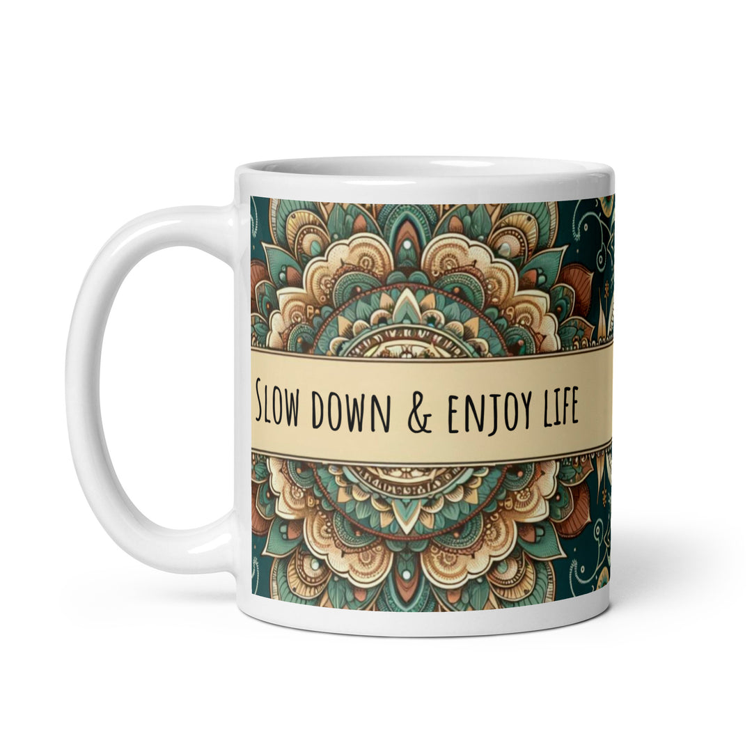 White ceramic mug with a detailed green and beige mandala design and the phrase 'Slow Down & Enjoy Life' in the center.