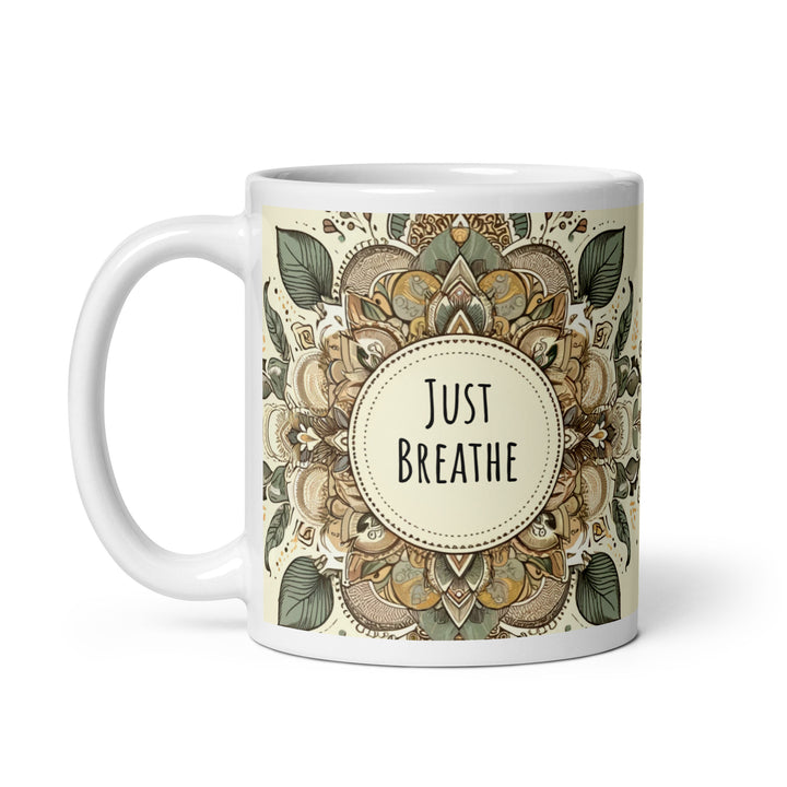 A white glossy mug with an intricate mandala design in earthy tones and the text 'Just Breathe' in the center.