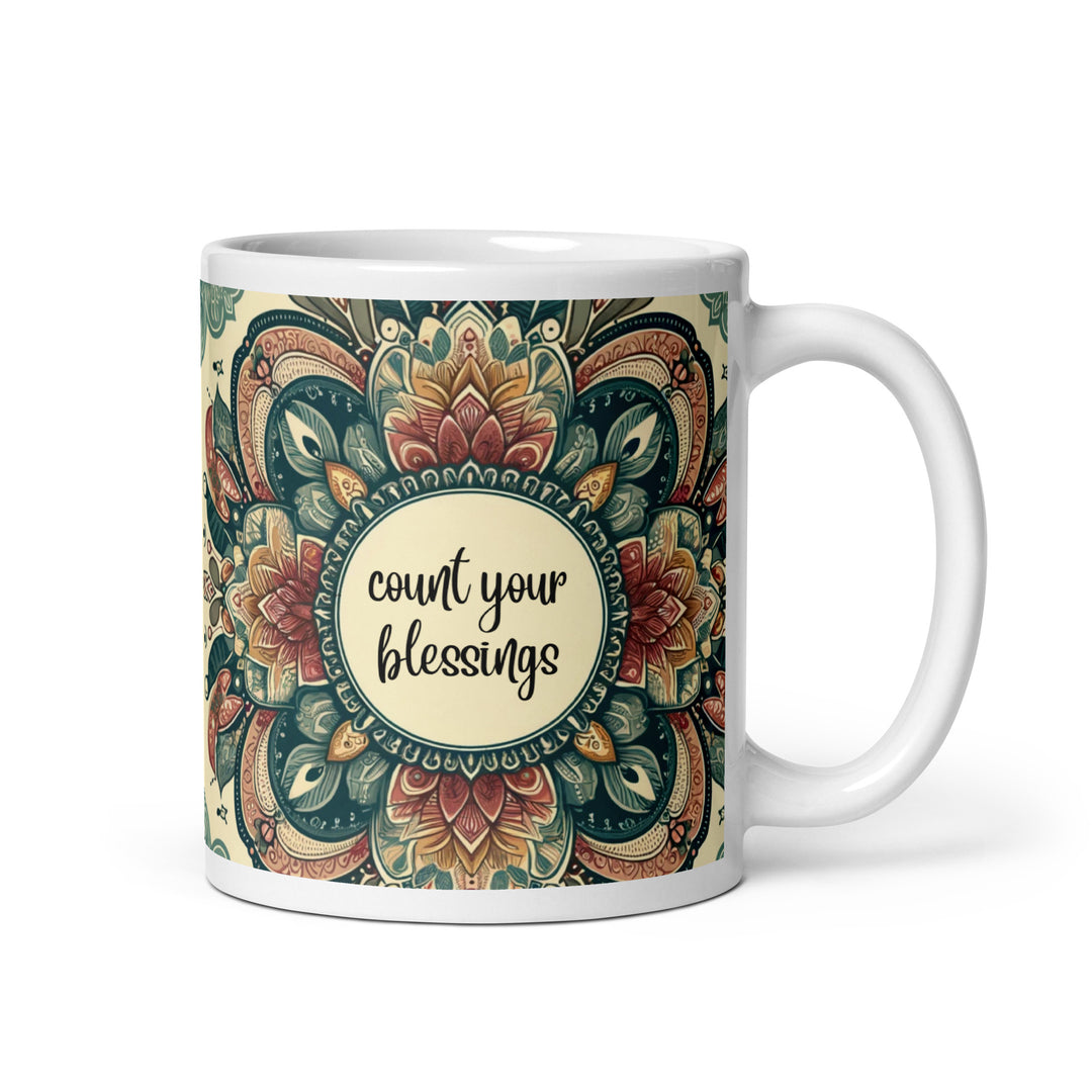 White ceramic mug with a detailed green, red, and gold mandala design and the phrase 'Count Your Blessings' in the center.