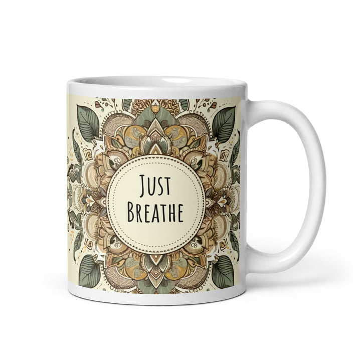 A white glossy mug with an intricate mandala design in earthy tones and the text 'Just Breathe' in the center.