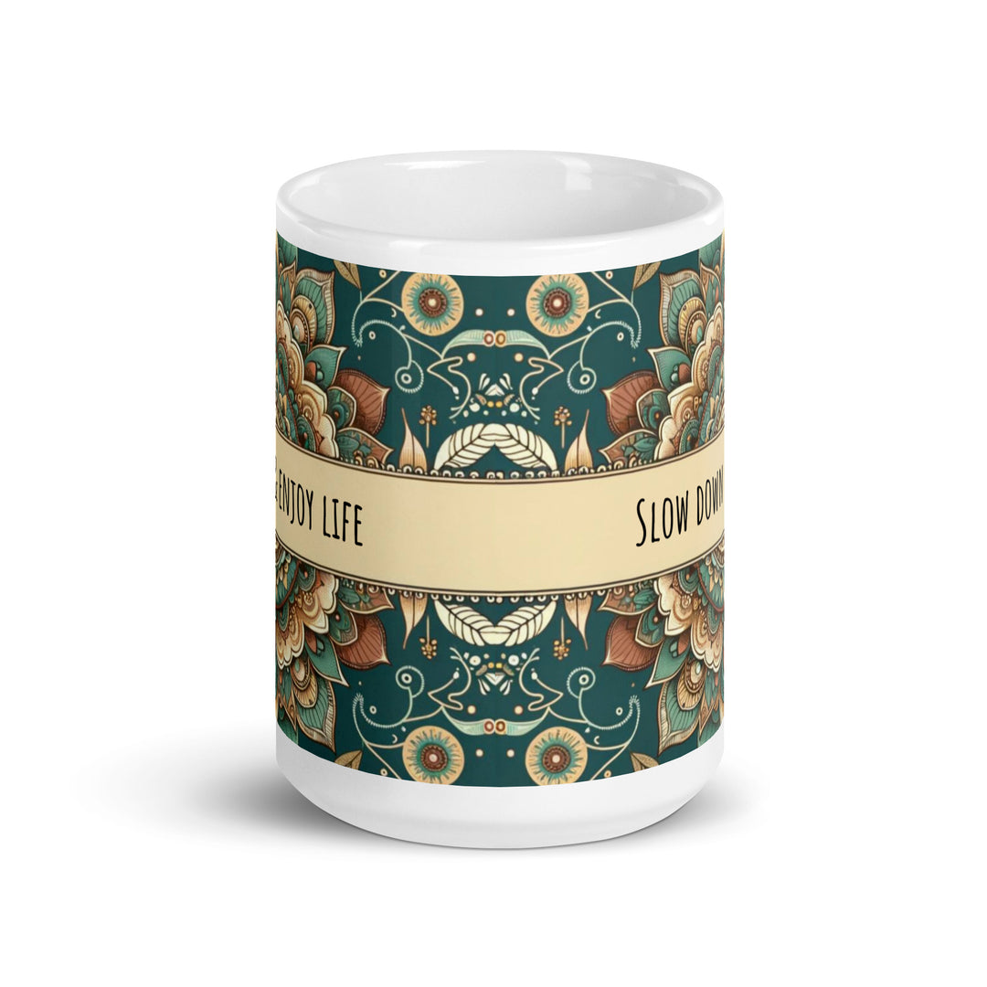 White ceramic mug with a detailed green and beige mandala design and the phrase 'Slow Down & Enjoy Life' in the center.