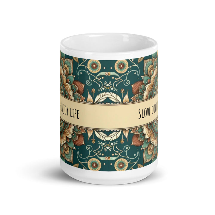 White ceramic mug with a detailed green and beige mandala design and the phrase 'Slow Down & Enjoy Life' in the center.