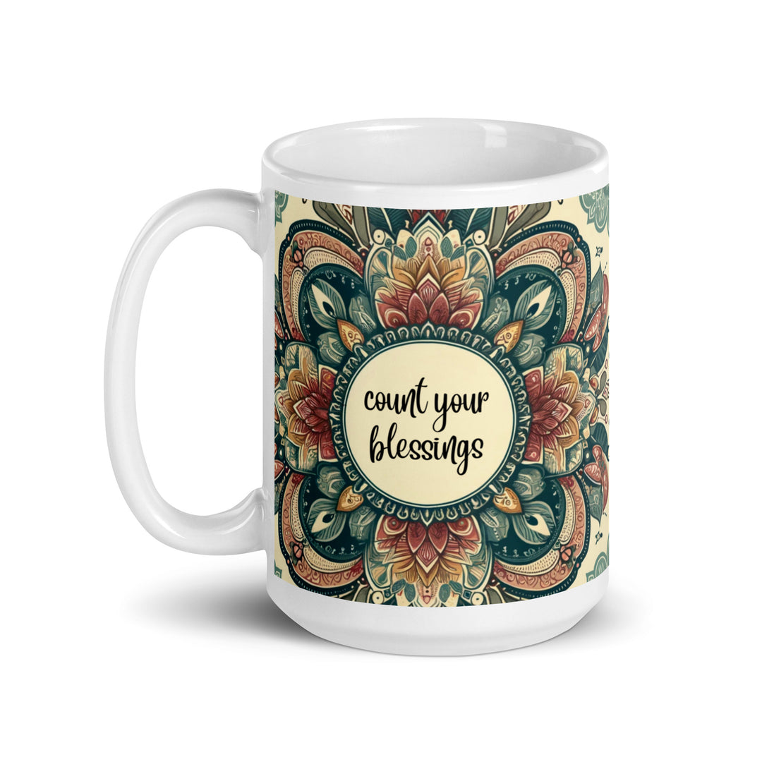 White ceramic mug with a detailed green, red, and gold mandala design and the phrase 'Count Your Blessings' in the center.