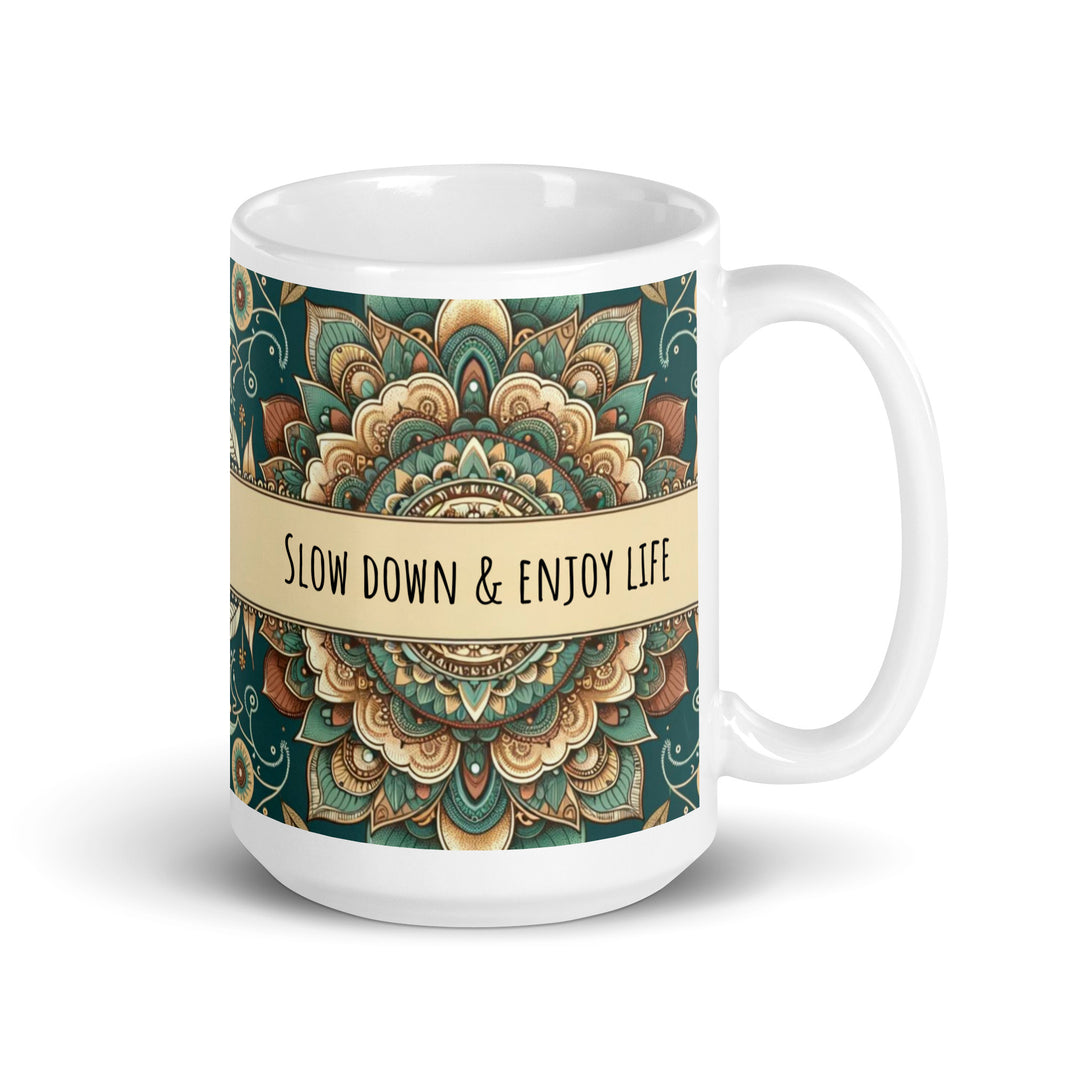 White ceramic mug with a detailed green and beige mandala design and the phrase 'Slow Down & Enjoy Life' in the center.